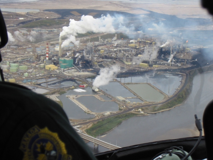 Athabasca oil sands processing facility, a large factory surrounded by water.