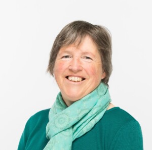 A photo of a woman standing in front of a plain background.