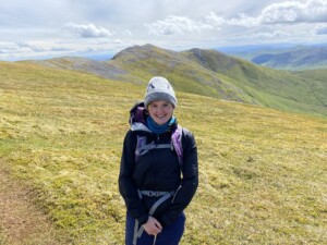 A photograph of a woman with mountains in the background.