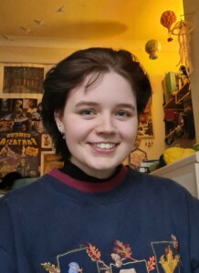 Head and shoulders photo of a woman, with a wall with posters behind.