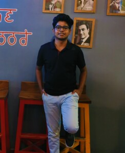 Photograph standing in front of a wall inside a cafe.