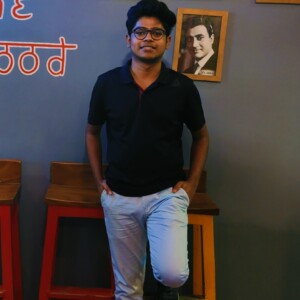Photograph standing in front of a wall inside a cafe.