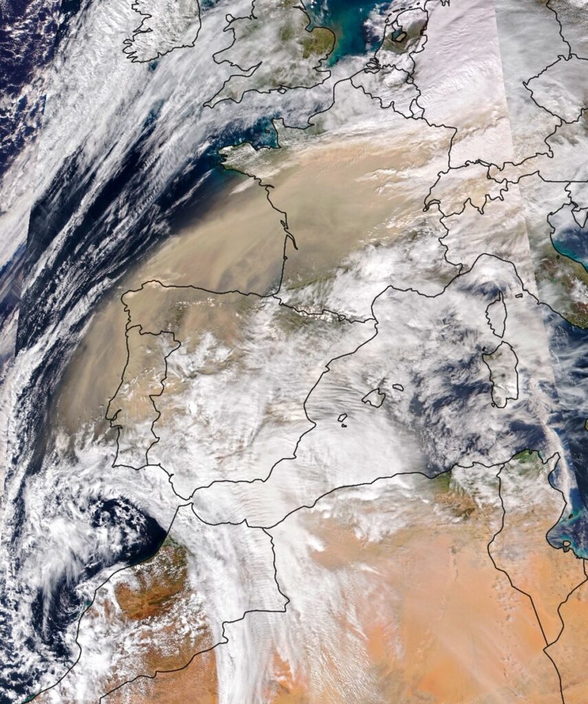 Satellite image showing a large dust cloud from the Sahara Desert moving over Spain, France, and the Mediterranean Sea, with visible cloud formations and weather patterns