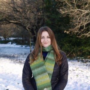 A photo of the upper half of a woman standing in front of a snowy landscape.