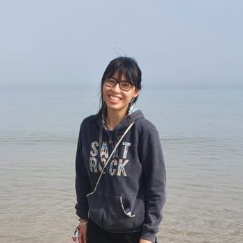 Photo of a woman standing in front of a large body of water.