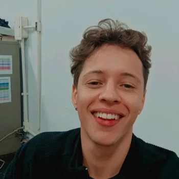 A photograph of the head and shoulders of a smiling man in an office environment.