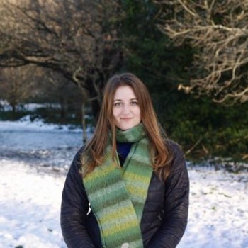 A photo of the upper half of a woman standing in front of a snowy landscape.