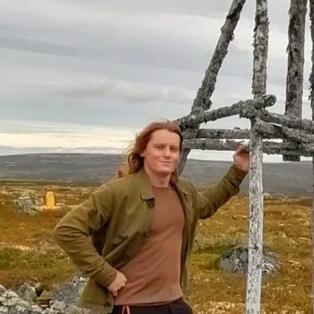 Photograph of a man standing in front of an upland hillside.