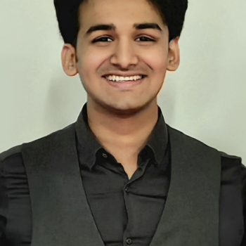 A photo of the head and shoulders of a man, standing in front of a plain background.